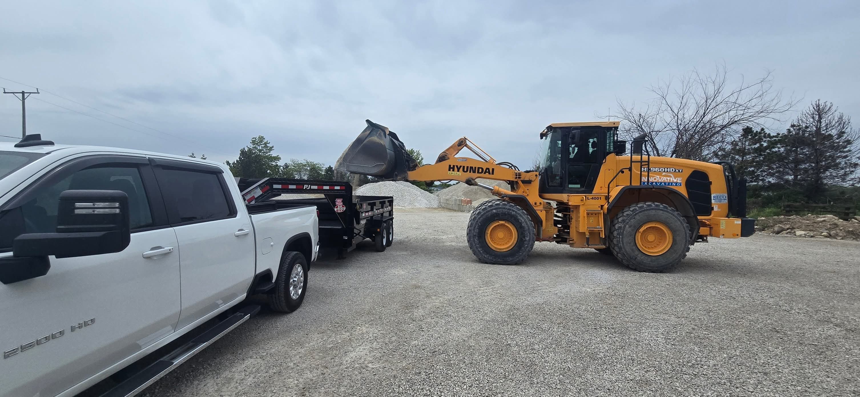 Dump trailer being loaded with gravel by wheel loader